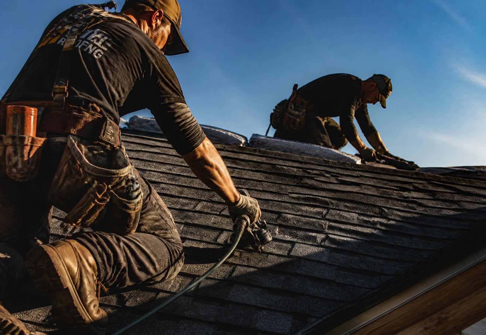 Roofing crew installing architectural shingles on a steep residential roof